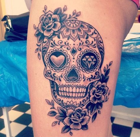 a woman's thigh with a sugar skull and roses tattoo on her leg,