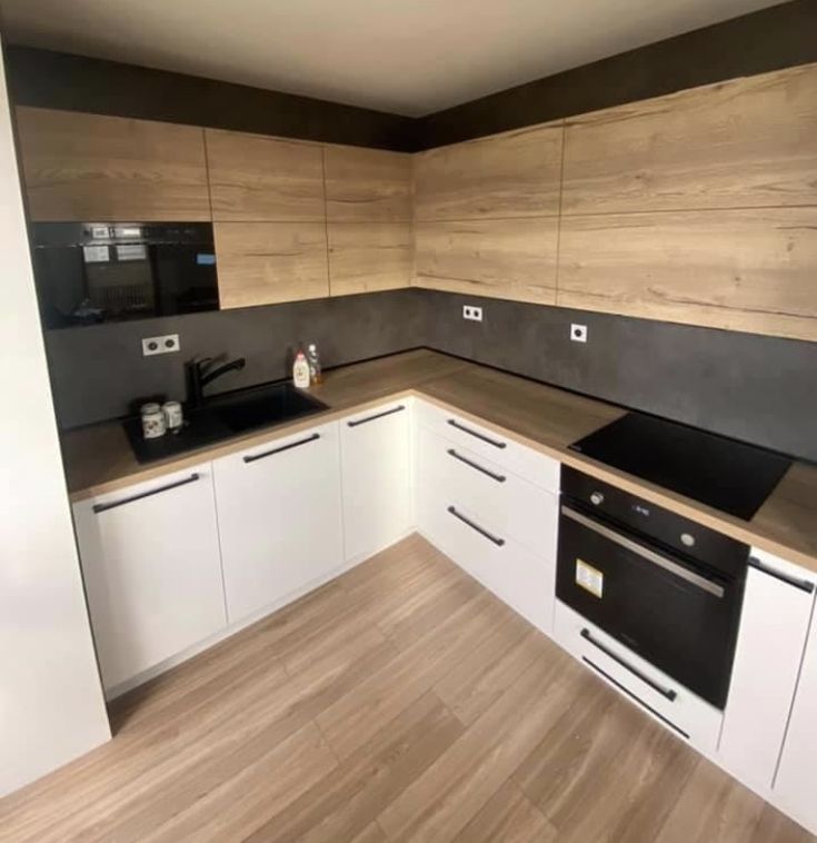 an empty kitchen with white cabinets and wood flooring on the walls is seen in this image