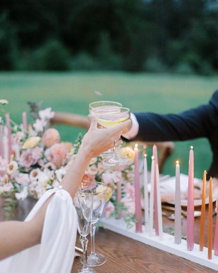 a man and woman toasting with wine glasses in front of candles on a table