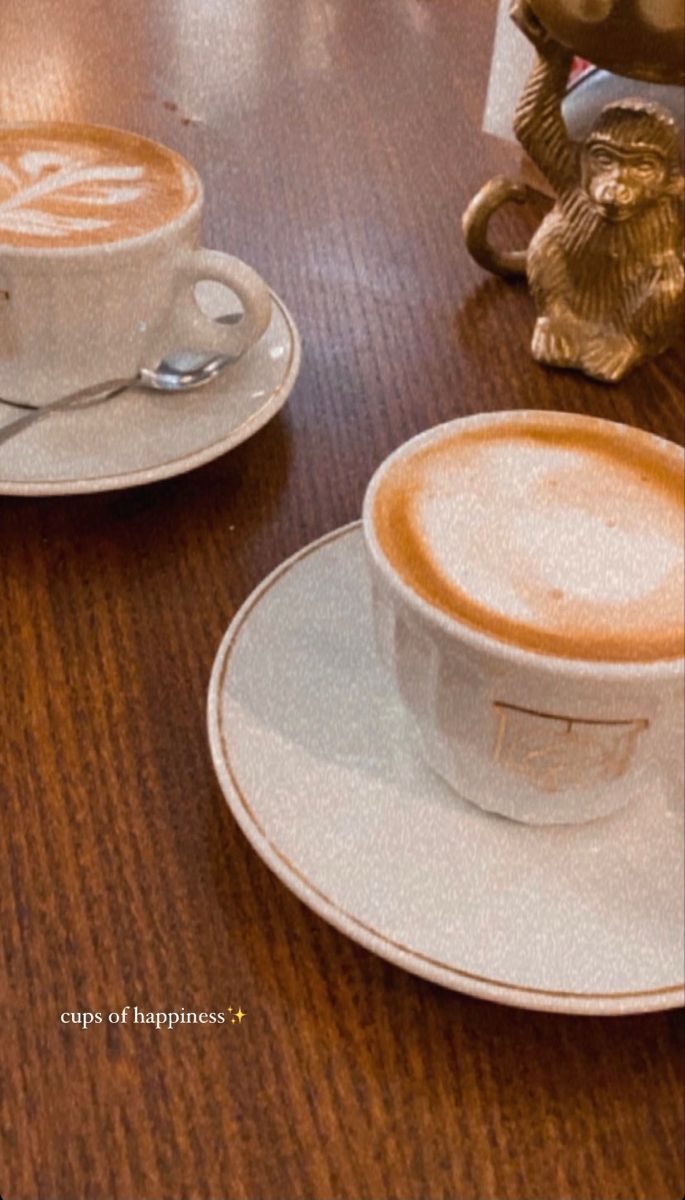 two cups of coffee sitting on top of a wooden table