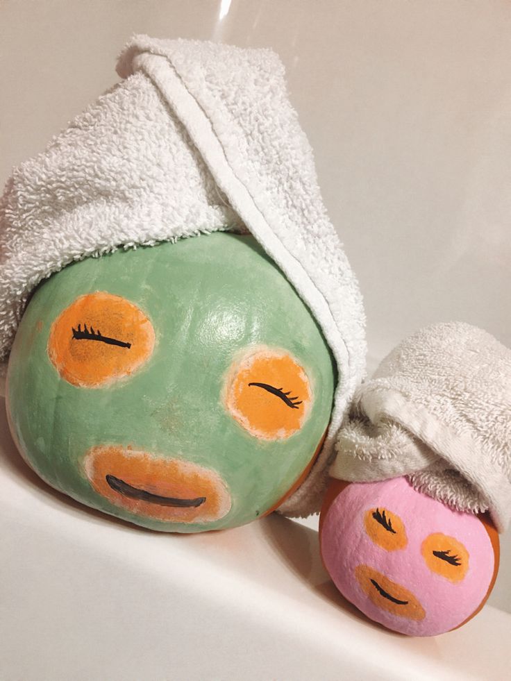 two green and pink balls sitting on top of a bath tub next to each other