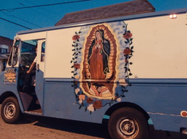 a blue and white truck with an image of the virgin mary on it