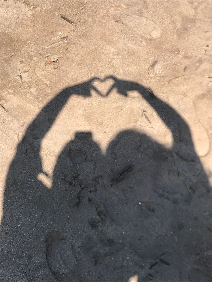 the shadow of a person making a heart shape with their hand on top of it