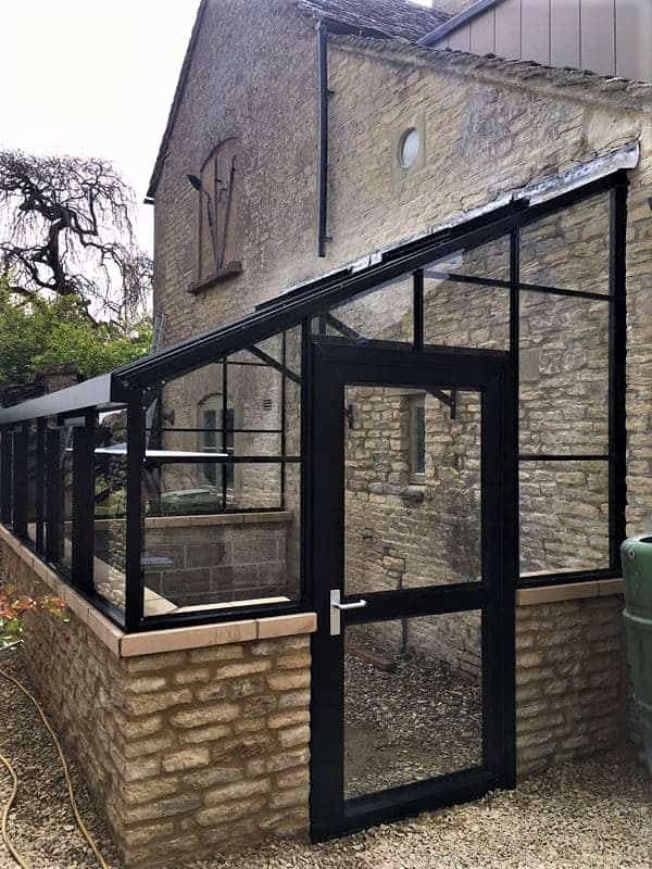 an old brick building with a glass enclosed area in the front and side of it