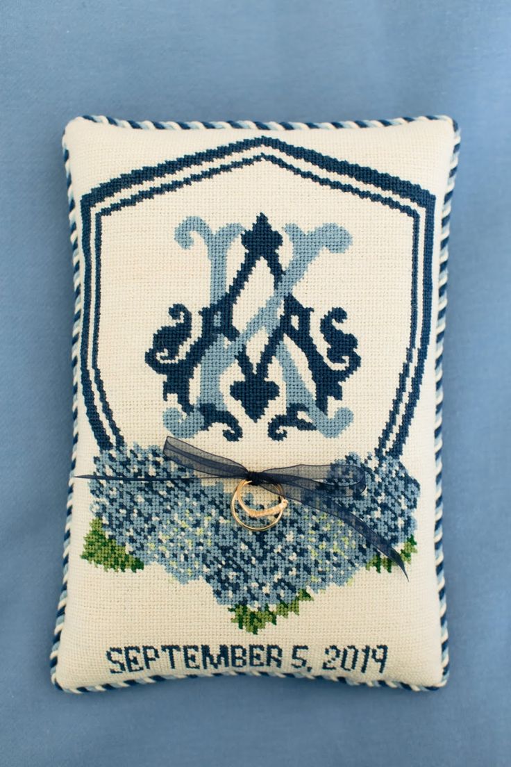 a blue and white cross stitched pillow with an emblem on it