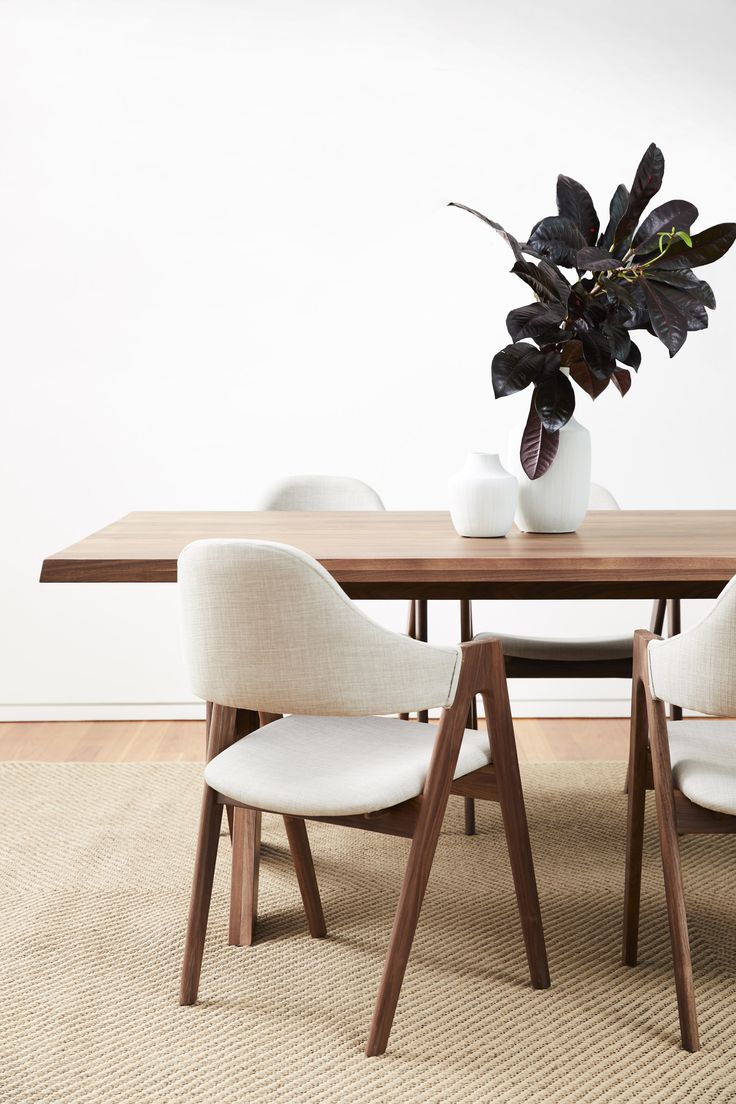 a wooden table with white chairs and a potted plant