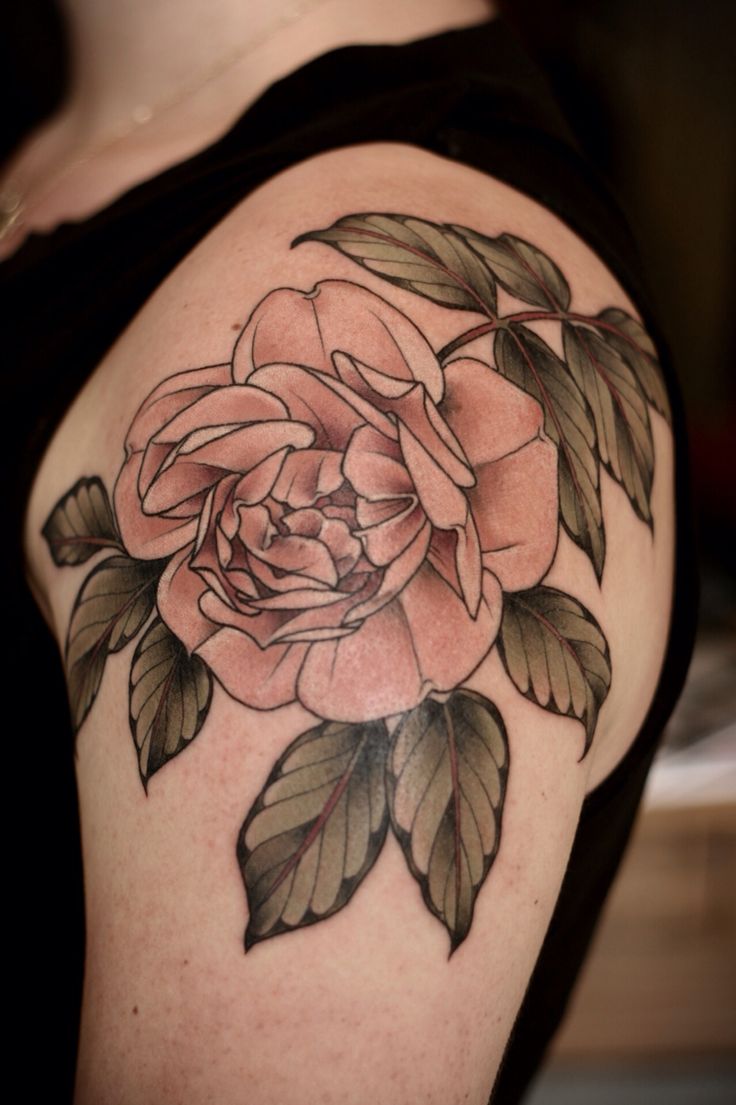 a woman's shoulder with a rose tattoo on it