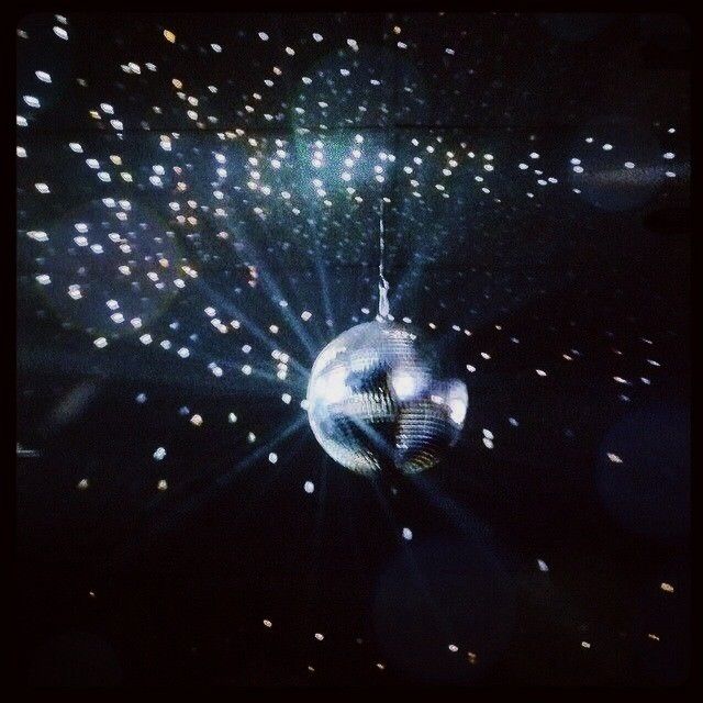 a disco ball hanging from the ceiling in front of some bright lights and sparkles