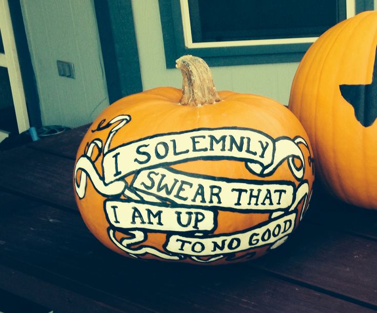 two carved pumpkins sitting on top of a wooden table with words painted on them