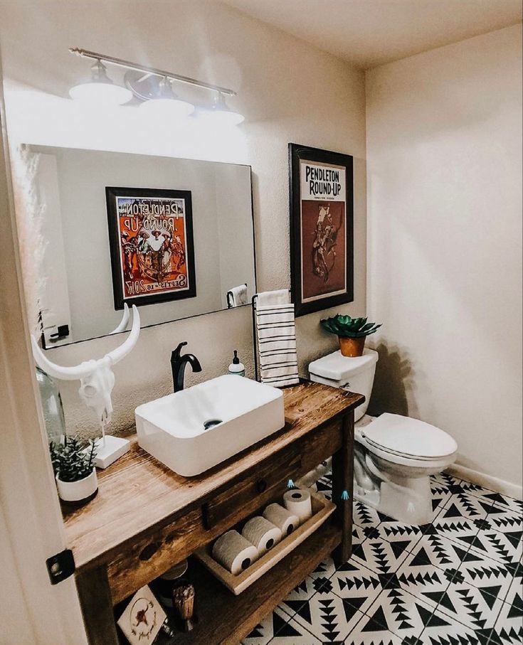 a bathroom with black and white flooring and artwork on the wall above the sink