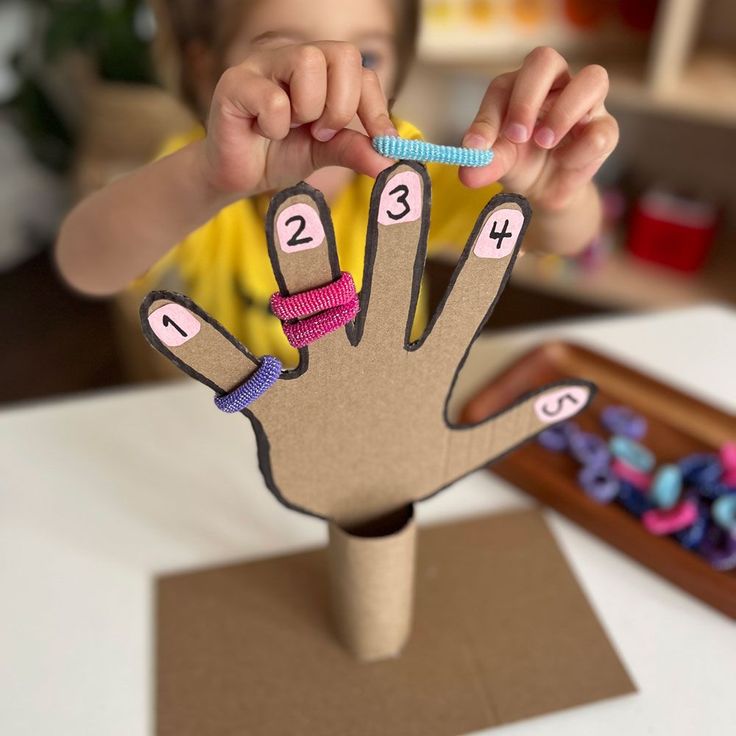 a young child holding up a paper hand with numbers on it