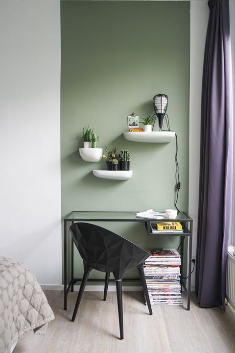 a bedroom with green walls and shelves on the wall, along with a black chair