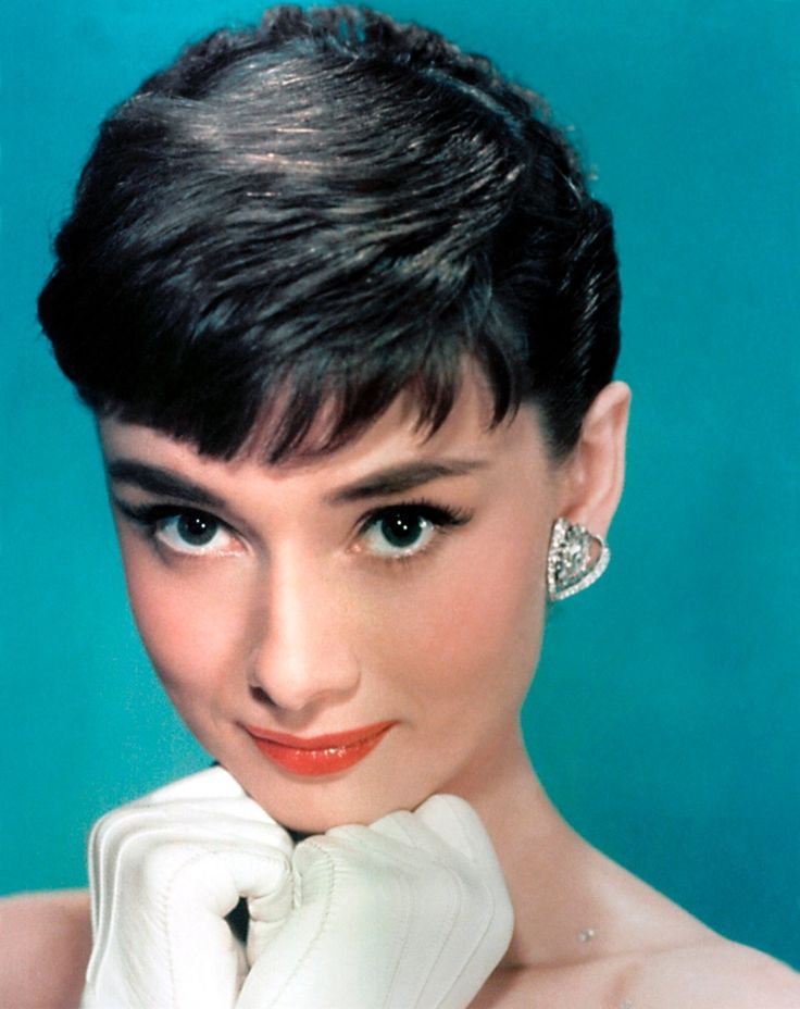 an old photo of a woman with short hair wearing white gloves and diamond ear rings