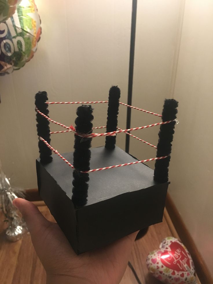 a hand holding up a black box with red and white string on it