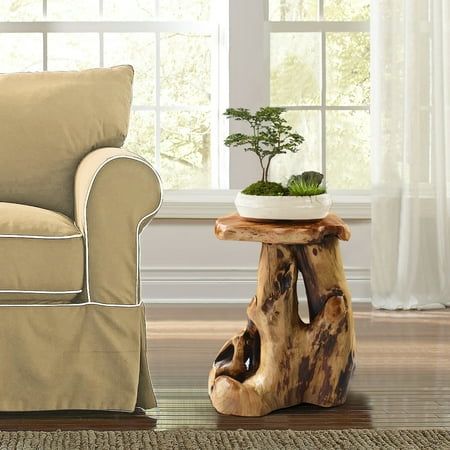 a living room scene with focus on the chair and tree stump side table that has a potted plant in it