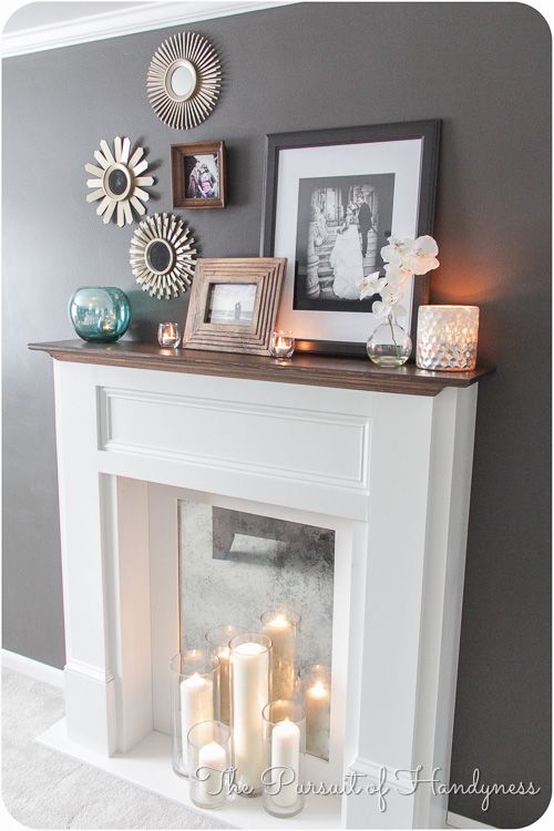 a white fireplace with candles and pictures on the mantel above it in a living room