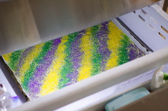 there is a cake that has been decorated with purple, yellow and green sprinkles