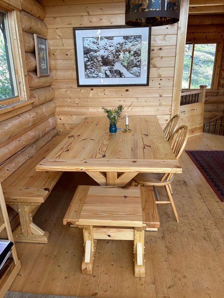 a wooden table and bench in a room with wood walls, flooring and windows