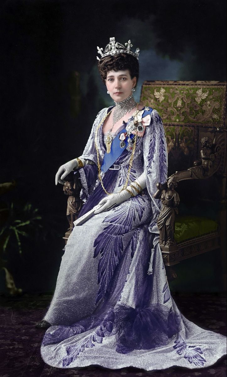 a woman wearing a tiara and sitting on a chair in front of a dark background