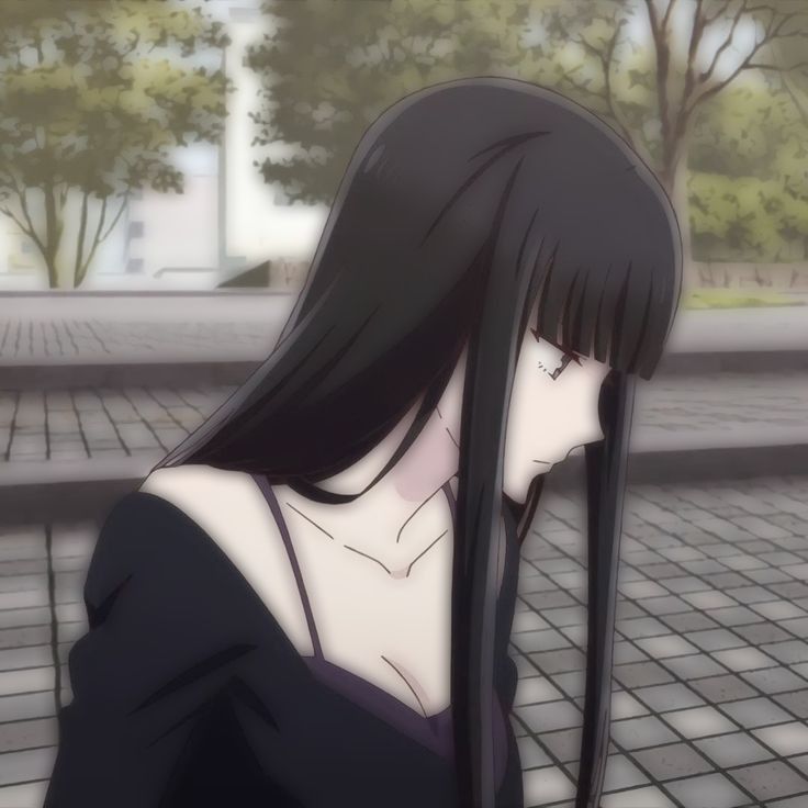 a woman with long black hair standing on a sidewalk