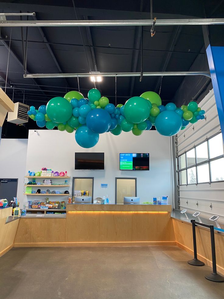 balloons are hanging from the ceiling in an open area with a counter and television screen