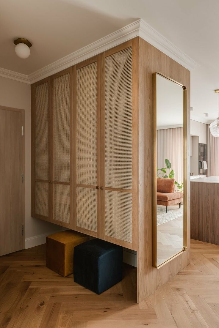 a room with wooden floors and cabinets in the corner, along with a mirror on the wall