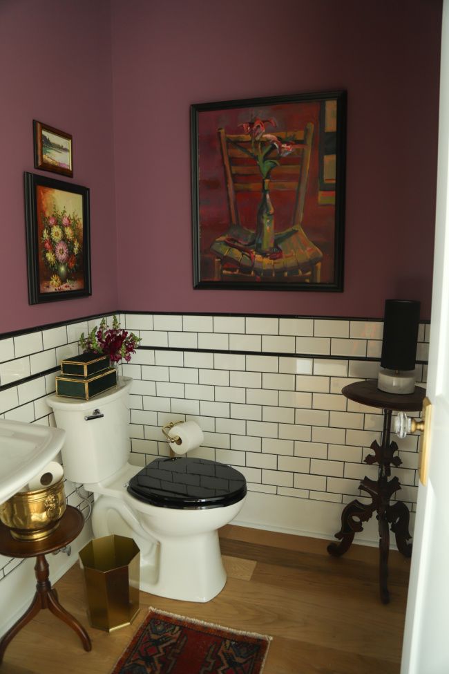 a bathroom with purple walls and white tiles on the wall, along with gold accents