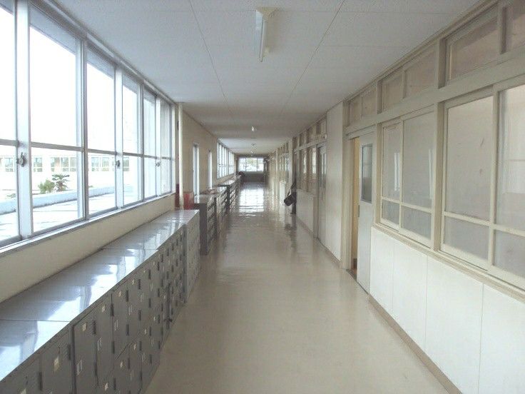 a long hallway with many mail boxes lined up along the wall and windows on both sides