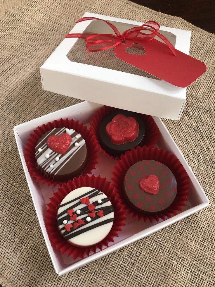 four decorated cupcakes in a white box