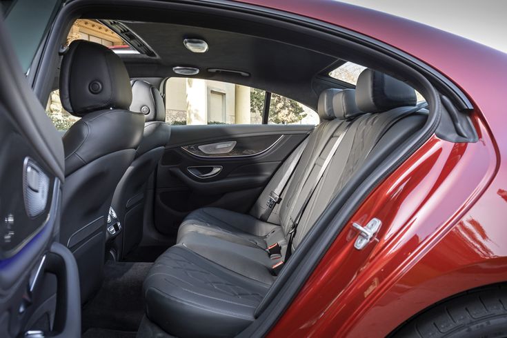 the interior of a red car with black leather seats and passenger side door ajar