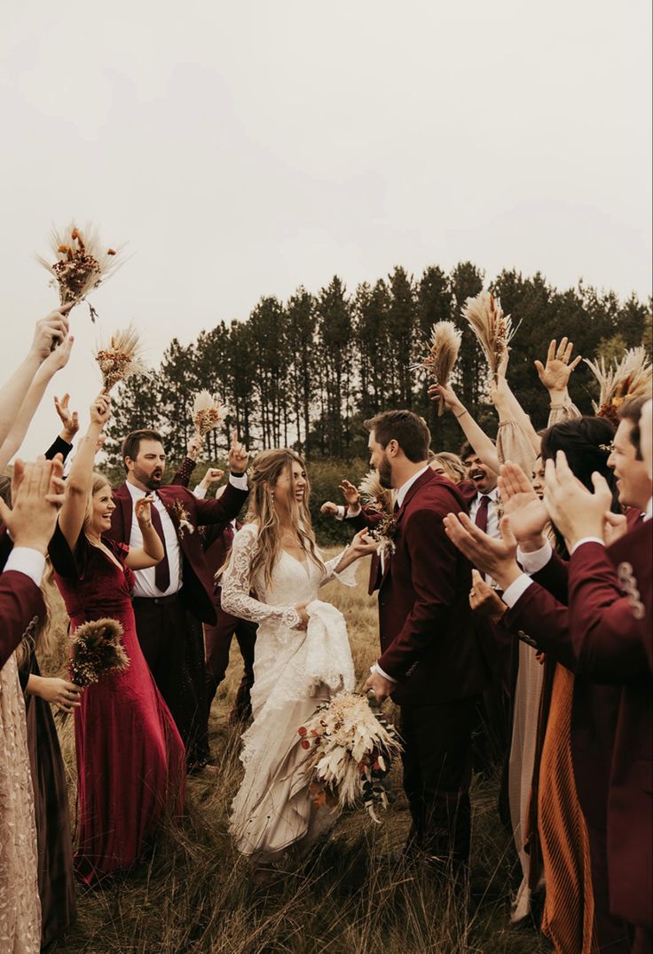 a group of people standing in a field with their hands up and throwing flowers into the air