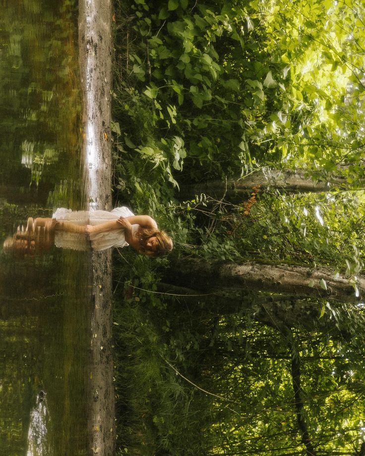 the reflection of a person's body in water with trees and bushes behind it