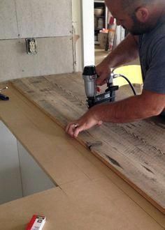 a man sanding wood on top of a counter with a grinder and drill