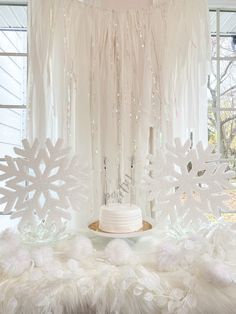 a white cake sitting on top of a table covered in snowflakes and frosting