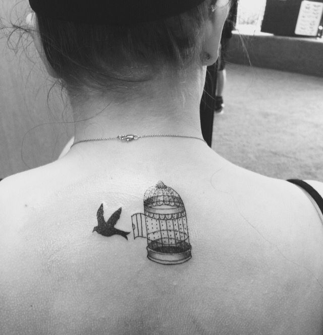 a woman with a bird and a cage tattoo on her back