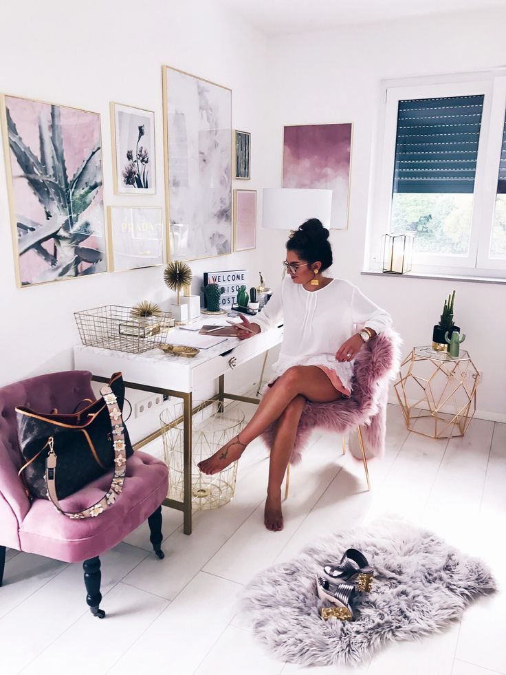 a woman sitting in a pink chair next to a desk