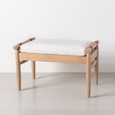 a wooden bench sitting on top of a hard wood floor next to a white wall