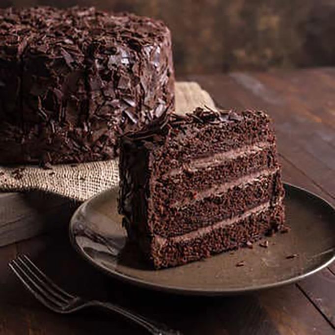 a piece of chocolate cake sitting on top of a plate next to a knife and fork