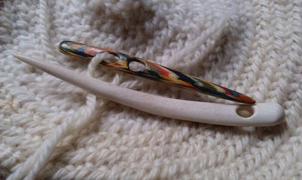 two toothbrushes sitting on top of a white knitted blanket next to each other