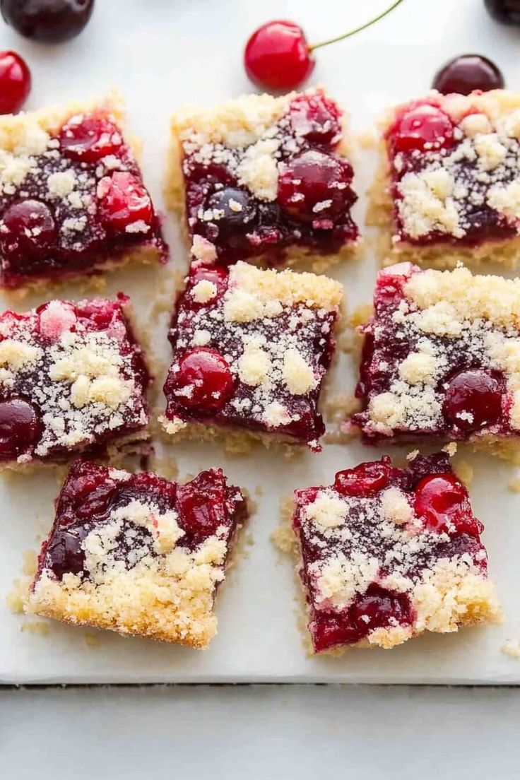 cherry crumbler bars on a white plate with cherries around the edges and in the background