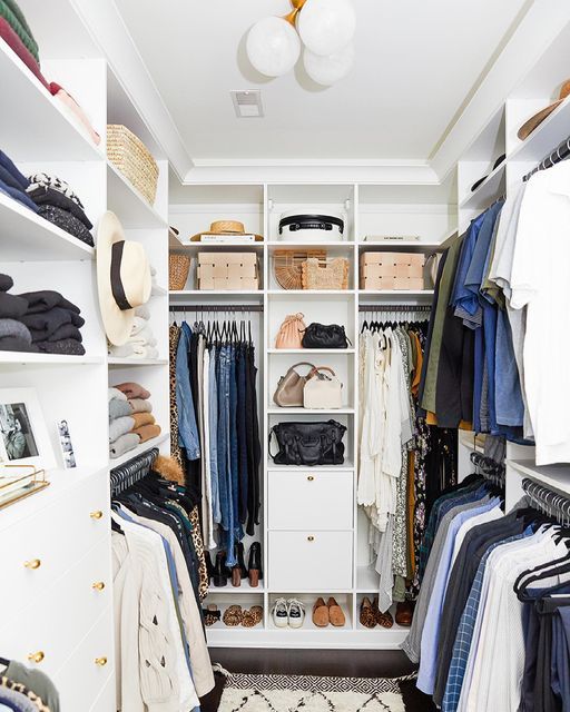 an organized closet with clothes, hats and other items on shelves in white painted walls