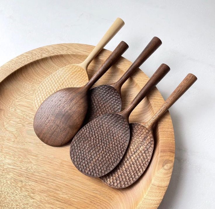 three wooden spoons and two wood spatulas on a plate