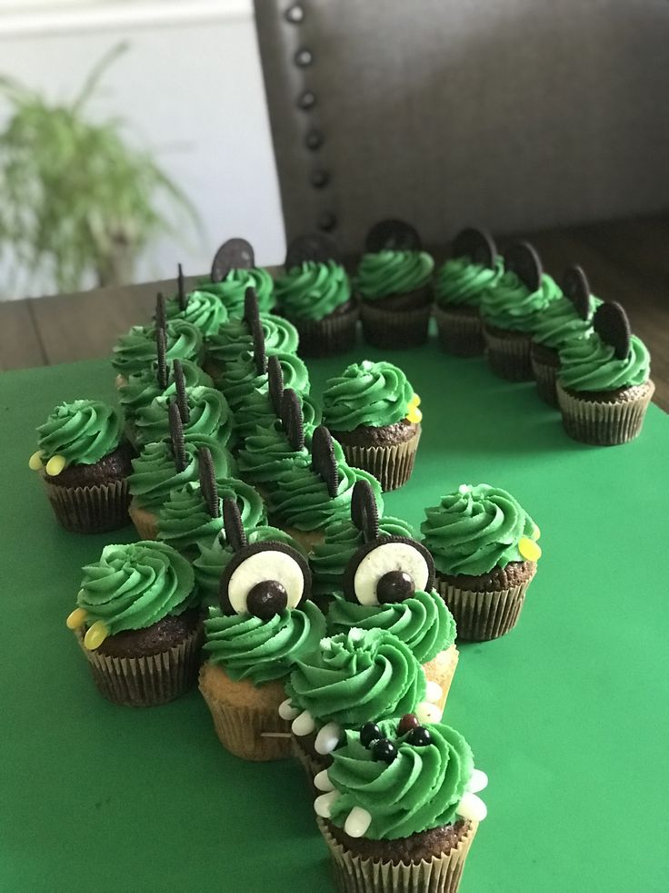 cupcakes with green frosting and googly eyes are arranged in the shape of a tree