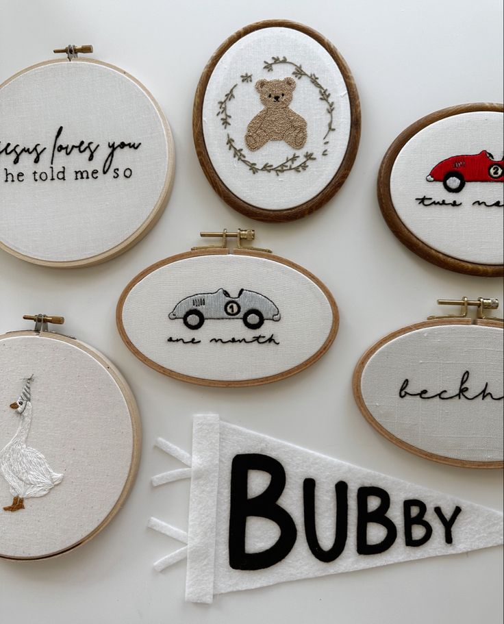 six embroidered hoop art pieces with words and pictures on them, including a teddy bear