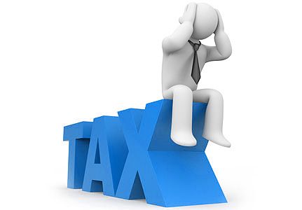 a person sitting on the top of a tax sign with his head in his hands