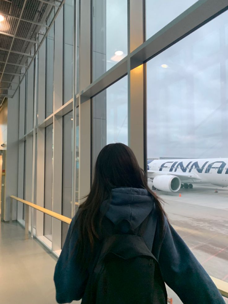 a woman is looking out the window at an airplane