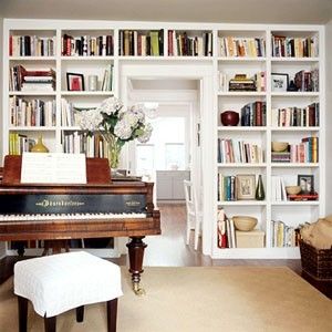 a living room filled with lots of furniture and bookshelves next to a piano