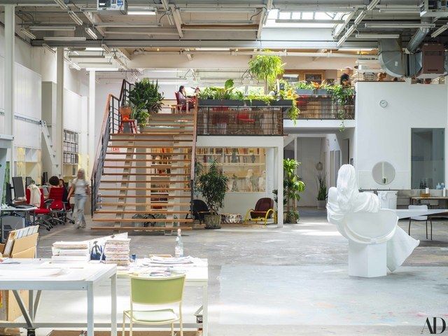 the interior of an office building with stairs and planters on the walls, while people sit at desks