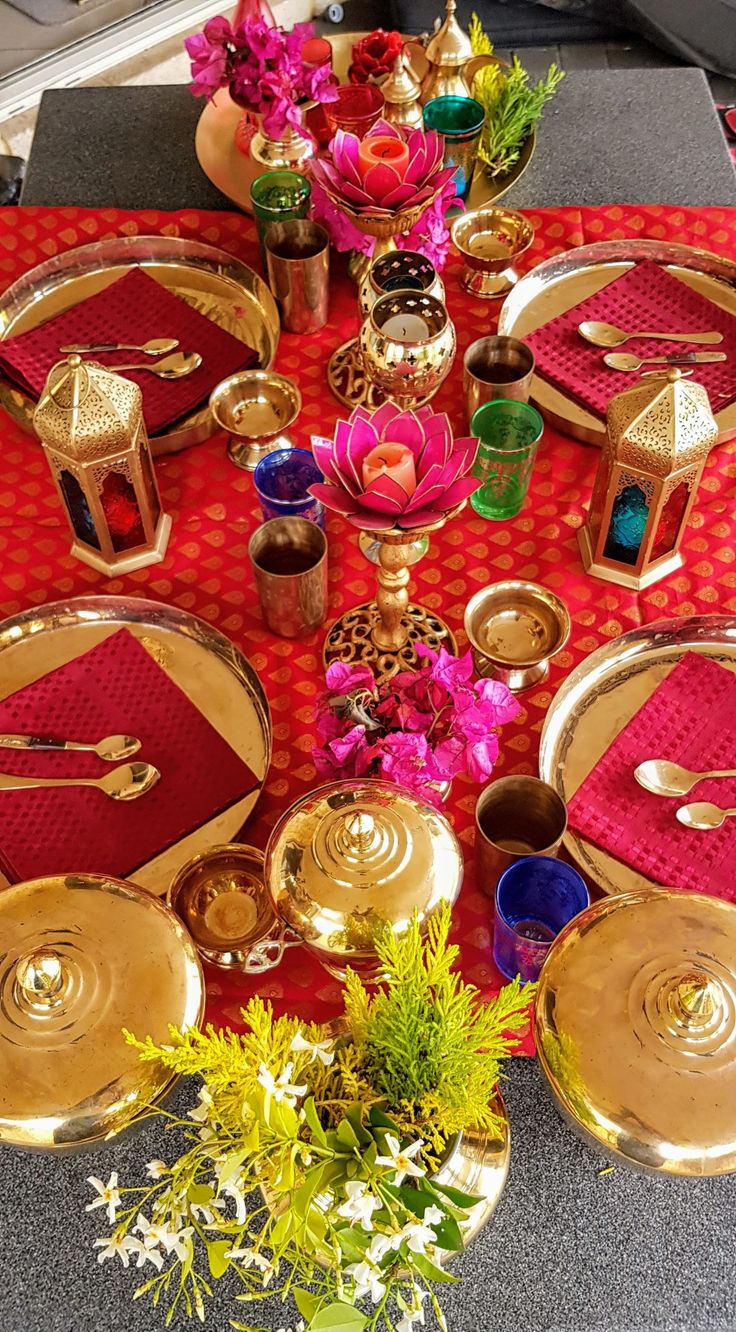 the table is set with red and gold plates, napkins, and flower arrangements