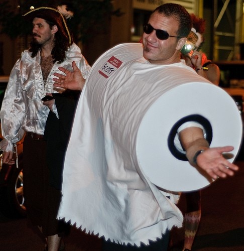 two men dressed in costumes are walking down the street with one holding a large white object